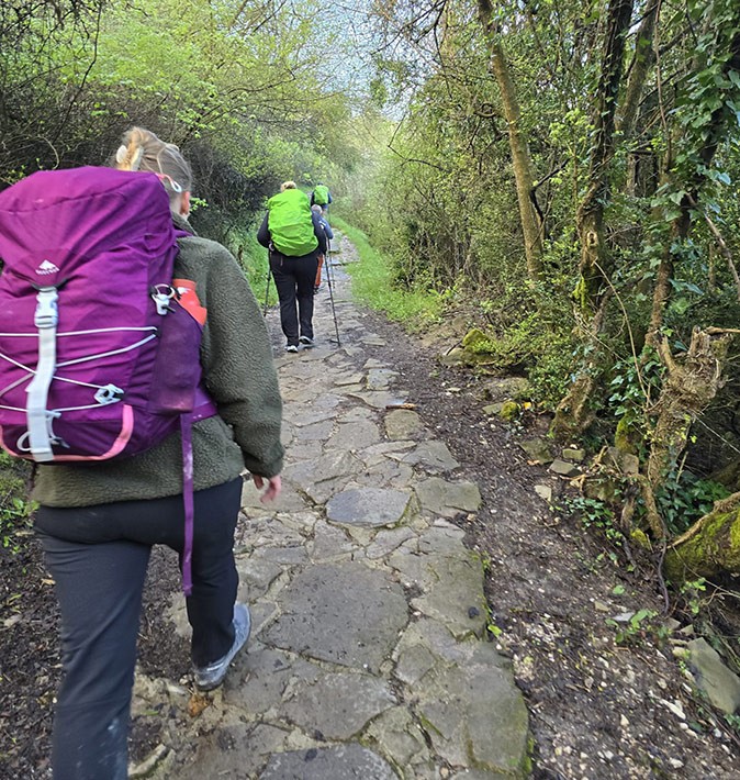 Packing for the Camino de Santiago when you work remotely A rocky path surrounded by greenery with 2 people walking with large backpacks