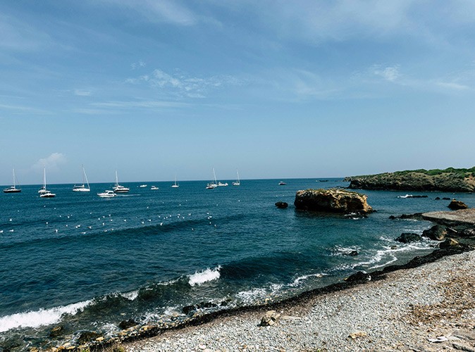 Yacht charter tips in Spain several boats achored just off a rocky beach
