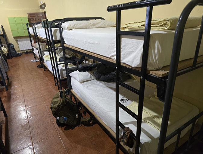 Albergues as accommodation along the Camino A row of black, metal bunk beds with white sheets