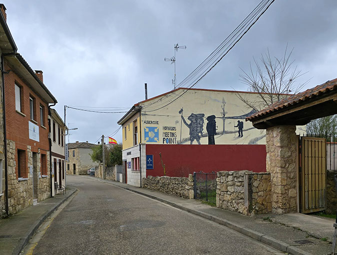 An albergue on the Camino de Santiago A Spanish street with an albergue with a mural and its name on the side of the building