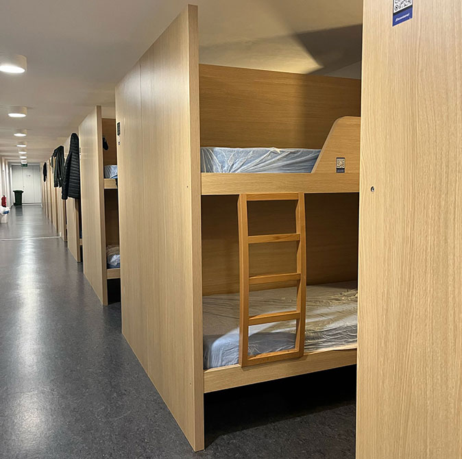 A pilgrims hostel on the Camino de Santiago A long row of wooden bunk beds in a light space