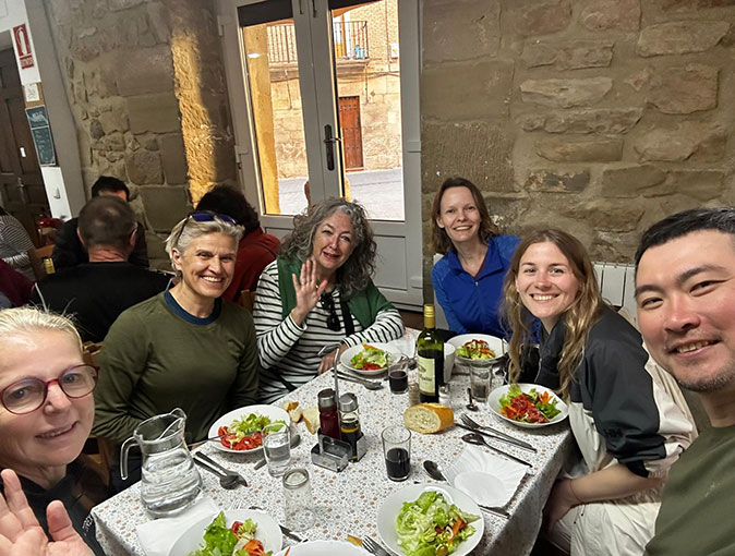 What to look for when choosing accommodation on the Camino 6 people sitting around a white table with food, smiling at the camera