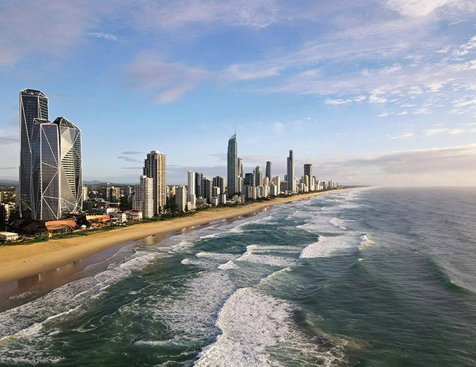 A coastline with golden sand, highrise buildings and waves hitting the beach
