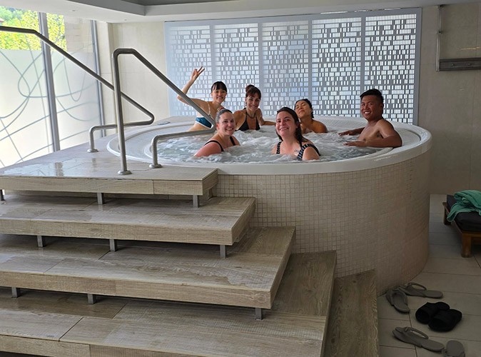 Going to the spa during our remote work retreat in Sinaia, Romania 6 people sitting in a hot tub smiling at the camera