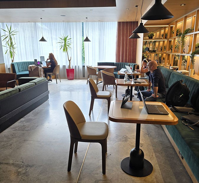 One of the 2 coworking spaces available during the coworking program in Sinaia, Romania A bright, modern looking cafe with several people working on their laptops at small wooden tables