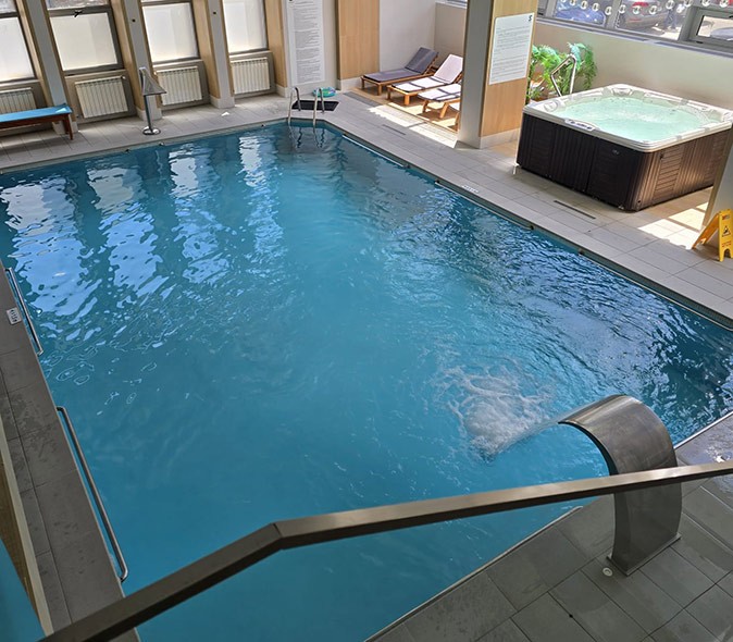 The pool at the spa that we had free access to as part of the retreat An empty pool with a jacuzzi next to it and large glass windows