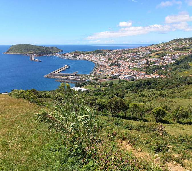 Exploring the Azores by sailboat Aerial view of a coastal town, a marina and green hills