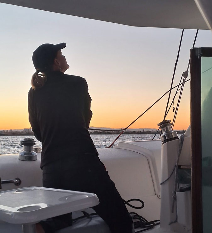 Sailing my boat into the sunset A woman on a sailboat at sunset looking at the sails while handling a rope
