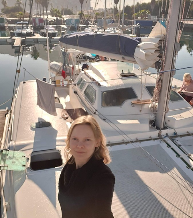 The first days of living on my sailboat Selfie of a blond woman standing on a catamaran with some other boats and palm trees in the background