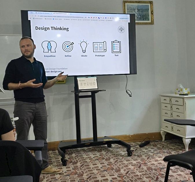One of the workshops organized during the digital nomad retreat A man standing in front of a screen with a presentation showing the text "design thinking" and several icons