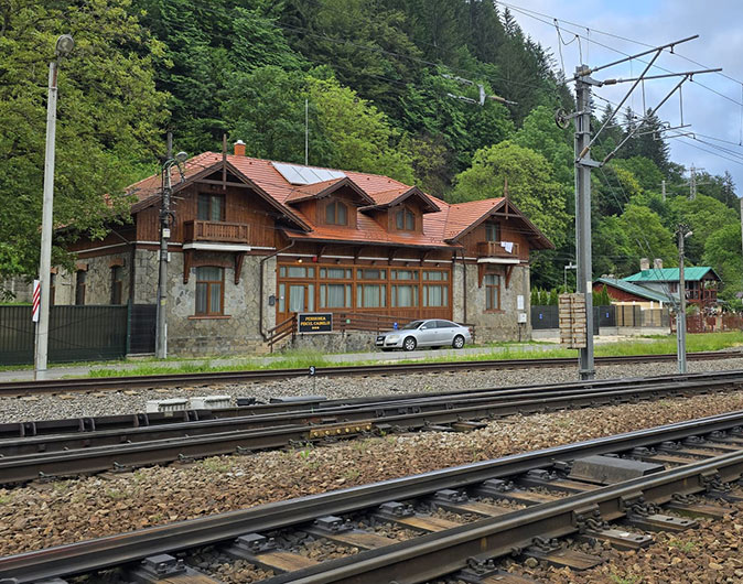 The second accommodation option for the nomad retreat in Sinaia A traditional looking wooden and stone hotel building with a train track in front of it