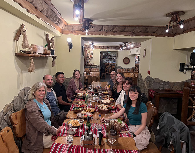 One of the many dinners the retreat organized 8 people sitting at a long table in a restaurant smiling at the camera