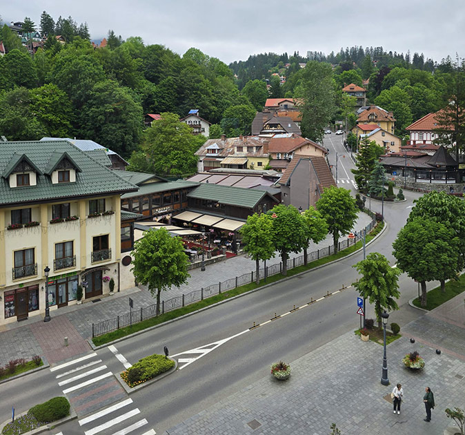 A rural coliving retreat in Romania Aerial view of the main street of a small town with yellow and white buildings with green and white roofs and a few pedestrians