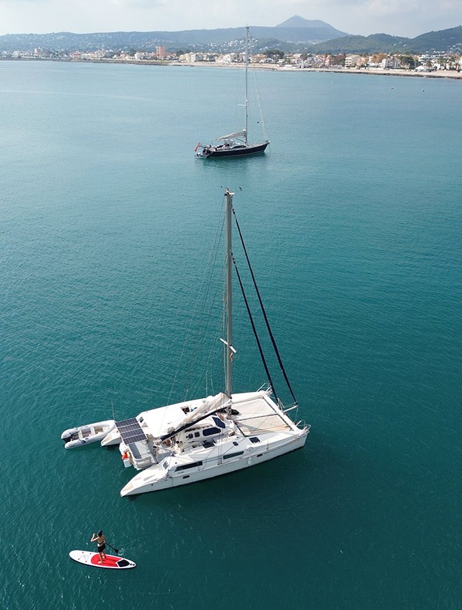 Paddleboarding around my catamaran 2 sailboats anchored off the coast and a woman on a paddleboard