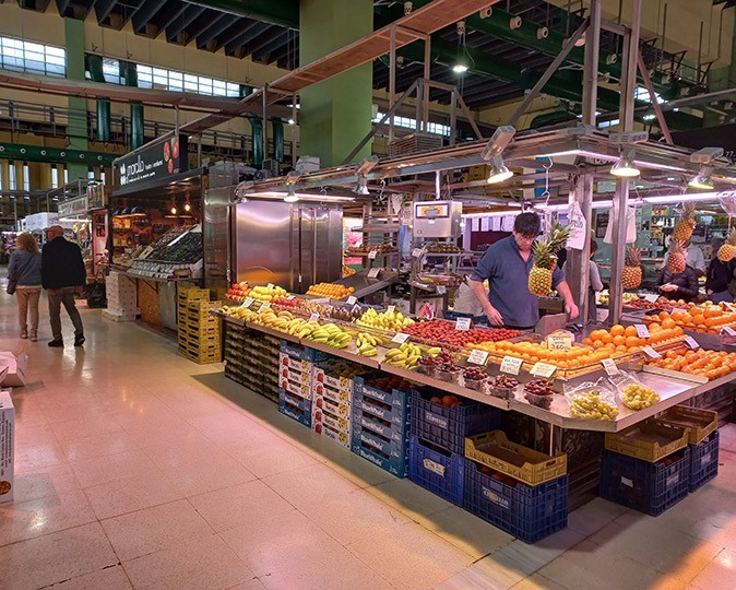 Spanish life An indoor market showing a fruit stand with a man behind it