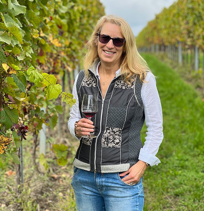 Solo traveling as a woman over 50 A blond woman standing in a vineyard holding a glass of red wine
