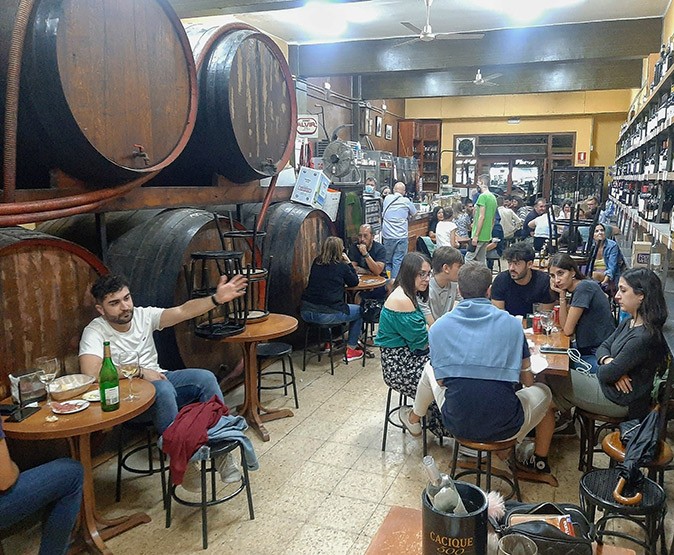 The pace of life in Spain A busy bar with small tables and stools and large wine barrels on the side