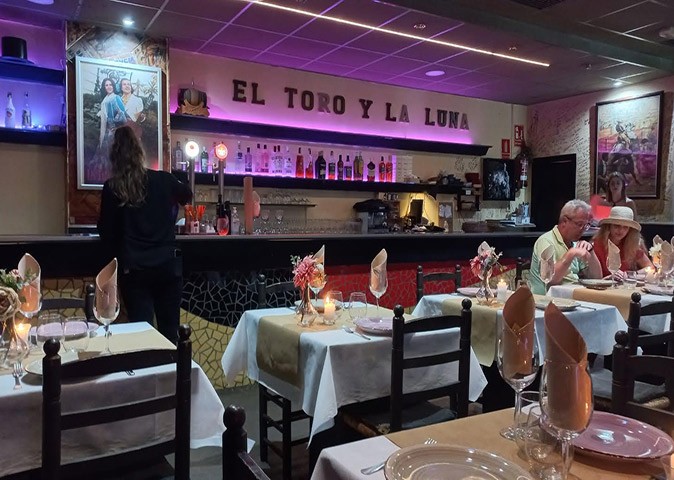 Things to know about life in Spain A nearly empty restaurant with small tables with white tablecloths, wooden chairs and a bar in the background