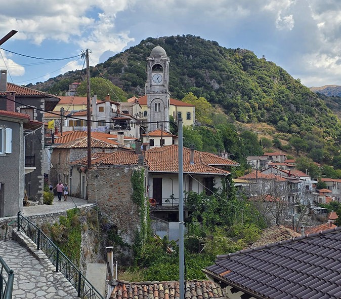 Dimitsana, a potential digital nomad destination in Greece Aerial view of a Greek village with stone buildings, orange roofs, a bell tower and green hills
