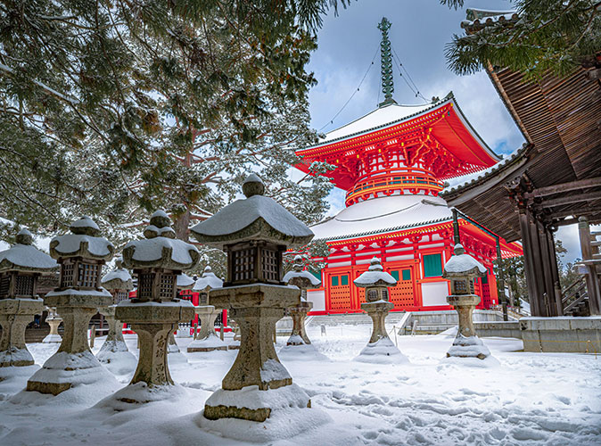 Winter retreats in Japan A snow covered landscape with a large red temple in the backgroun plus some brown shrines and a tree