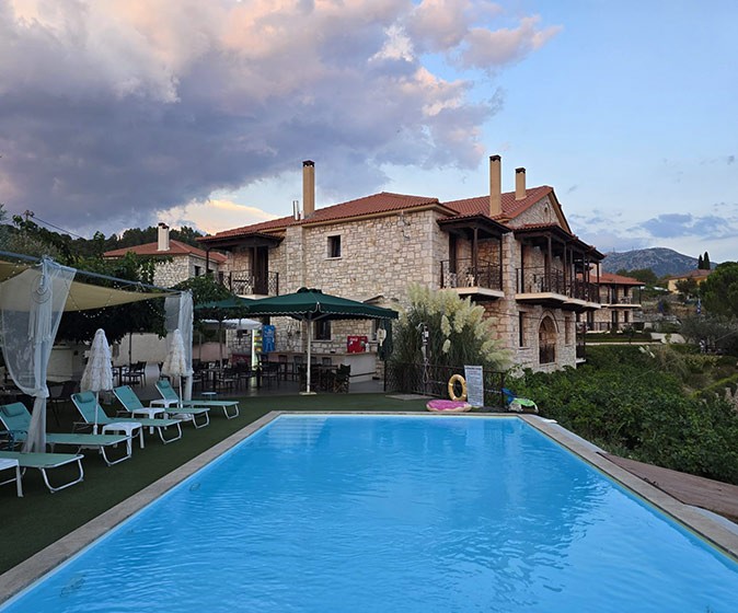 Our coliving space in Greece with Tursi Digital Nomads A large swimming pool with some sun loungers and umbrellas, with a large stone building in the background