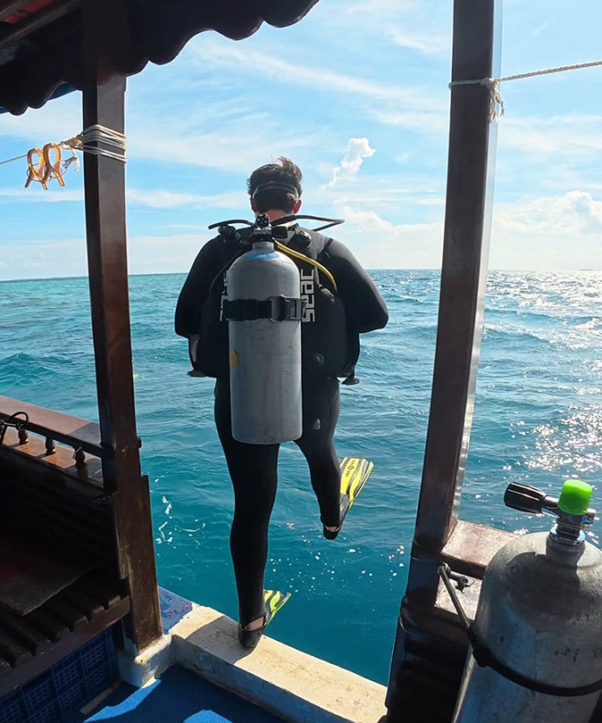 A scuba diver stepping off a boat into the water ready for a dive
