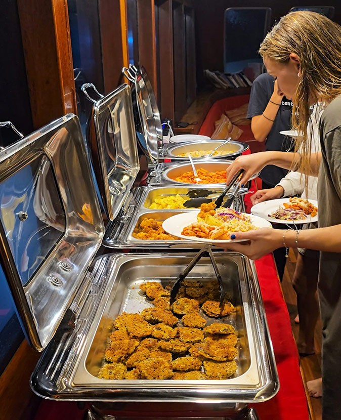 Silver trays offering buffet style food with people serving themselves