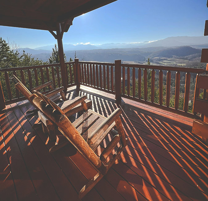 Where to stay in Gatlinburg The porch of a wooden cabin showing 2 wooden chairs looking out over green mountains