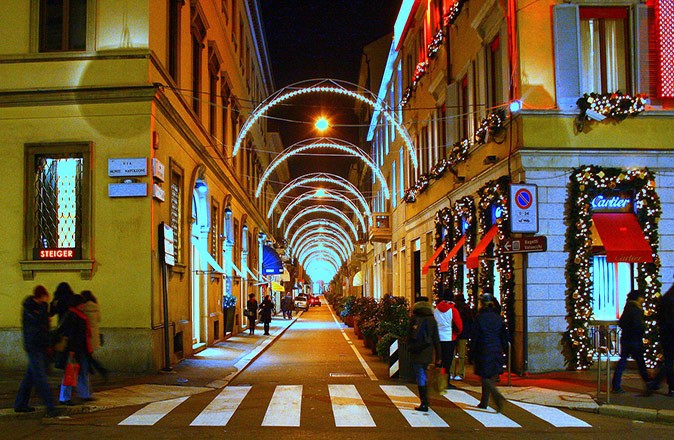 An Italian street at night with Christmas lights and several people