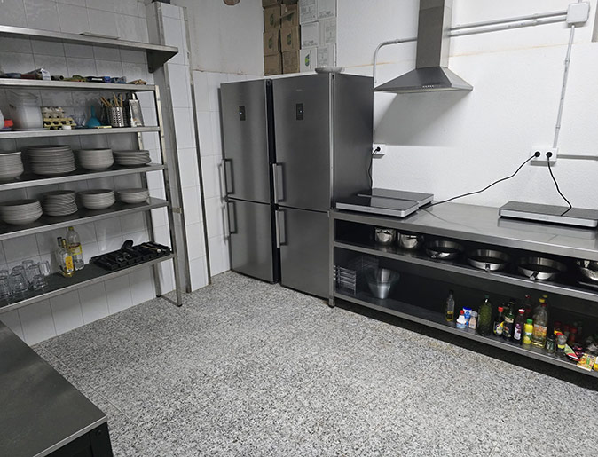 A spacious, industrial looking kitchen with stainless steel appliances and a gray floor