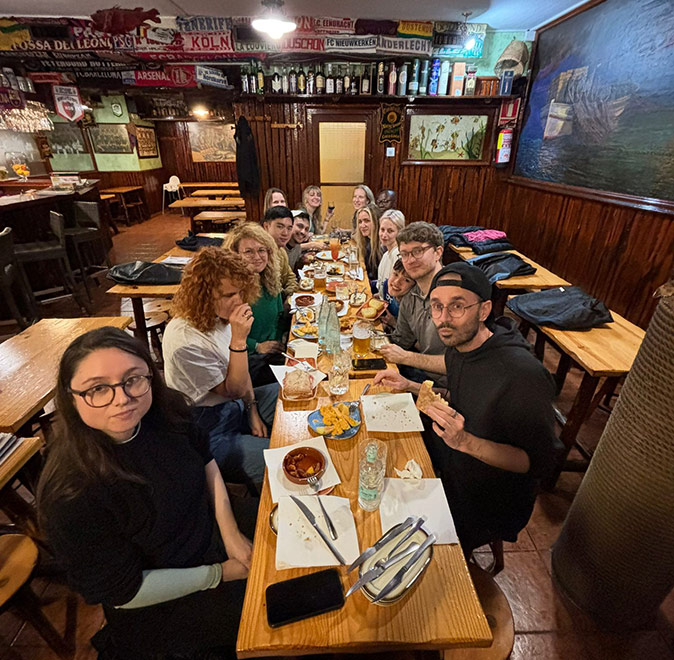 A group of people sitting at a long wooden table inside a restaurant with a wooden interior