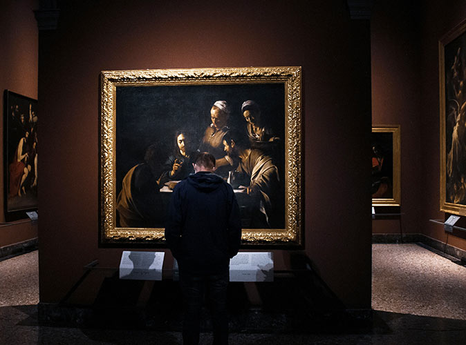 A man looking at a painting inside a dimly lit museum
