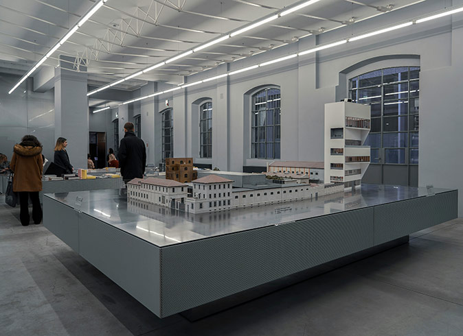 Interior of a bright, white museum with several people in winter coats