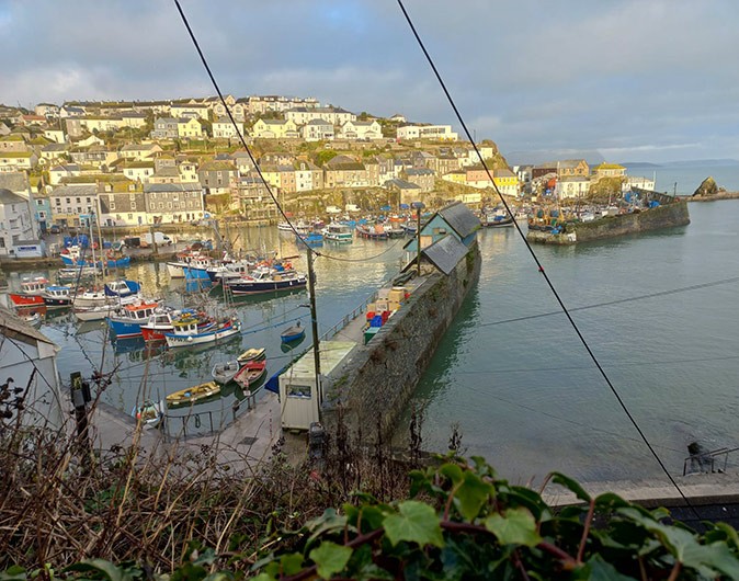 A typical town worth visiting in Cornwall A small port with fishing boats with white and gray houses built on a hill in the background