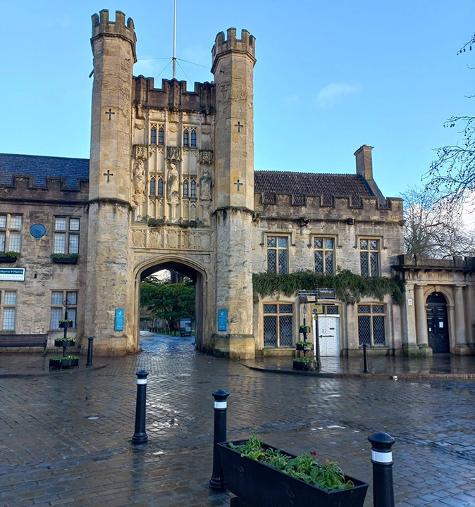 One of many British towns to visit A historic town gate with two towers and a cobbled street in front of it