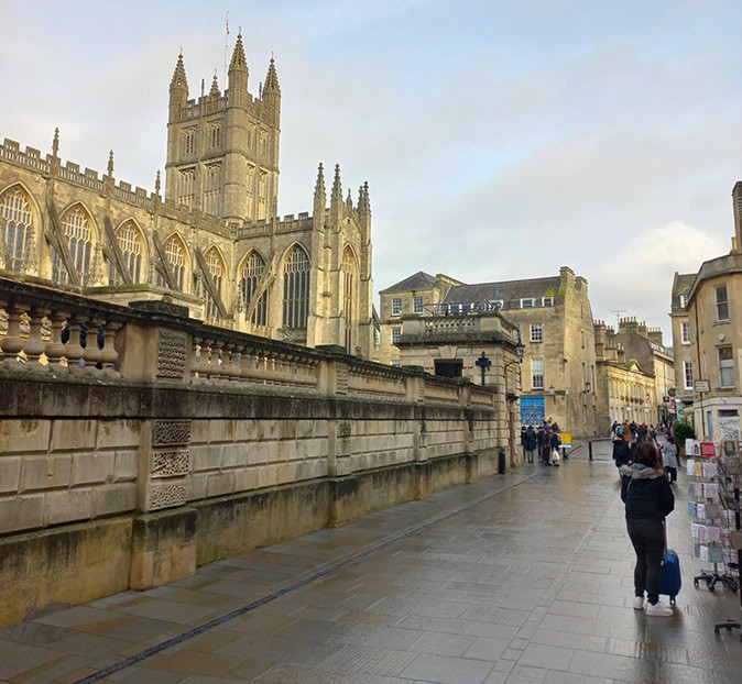 Bath, a beautiful British city with a rich history A pedestrianized street with several people, with a large historic abbey next to it