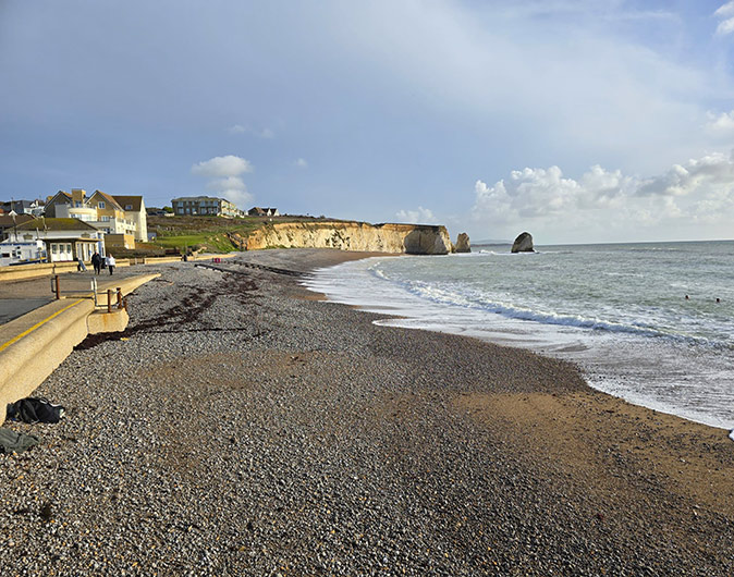The stunning coastline of the Isle of Wight is a unique thing to see in the UK A pebbly bech with steep, white cliffs in the background and some houses in front of that