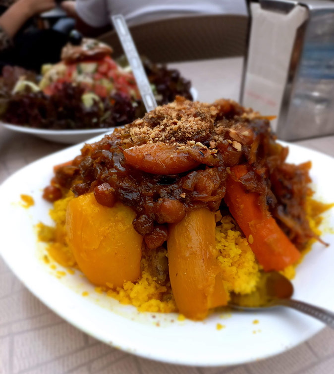 What you should know about living in Morocco A large plate of couscous with vegetables on a white table showing part of another dish out of focus in the background