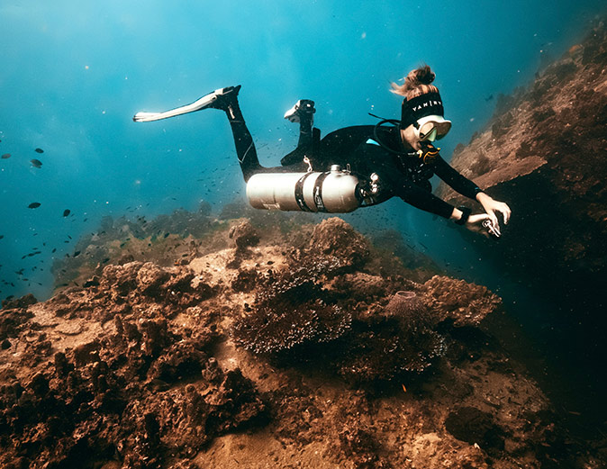 A female scuba diver swimming above a coral reef