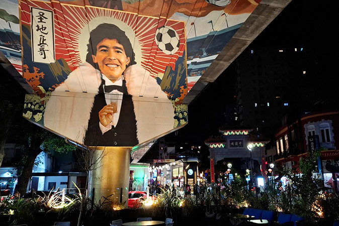Life in Buenos Aires, Argentina A large painting of Maradona in a city setting at night with buildings and traffic in the background