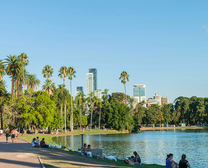 Enjoying life in Buenos Aires People sitting around a lake with palm trees, other greenery and high rise buildings in the background
