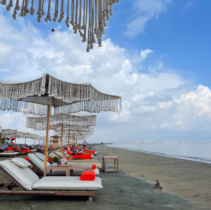 Enjoying life in Cyprus Sun loungers with white cushions, orange towels and gray umbrellas, lined up along a sandy beach