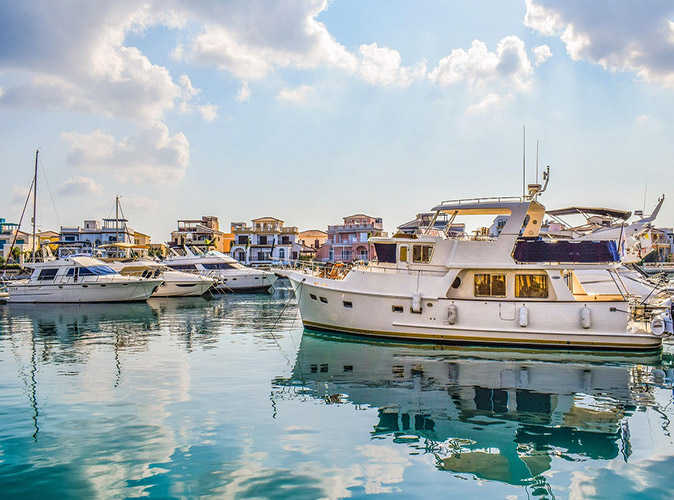 Expat life in Limassol A marina filled with expensive boats, with some white houses in the background