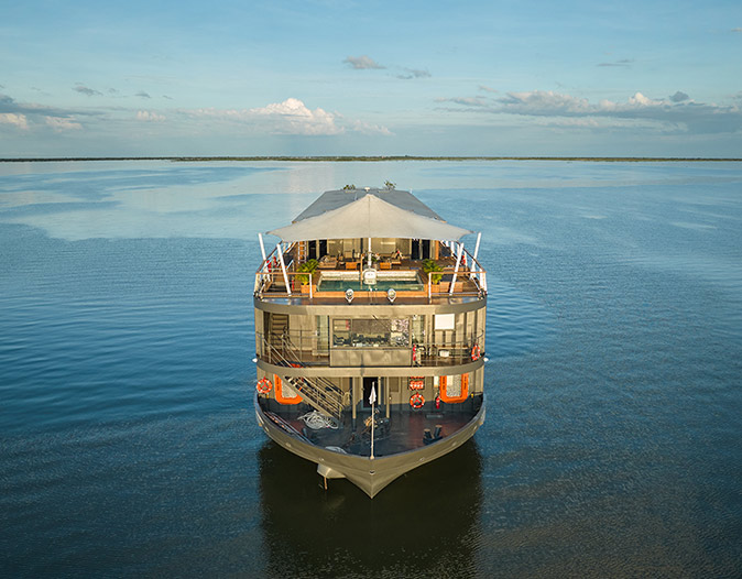 A luxury Mekong River cruise The back of a small cruise ship showing 3 decks, the top one with a swimming pool