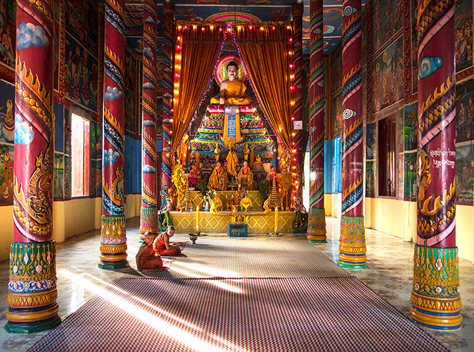 An excursion in Cambodia during the Mekong River cruise 2 Buddhists sitting inside a colorful Buddhist temple