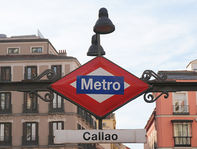 Tips for getting around Madrid A red and blue metro sign with the word 'Callao' under it and parts of apartment buildings in the background