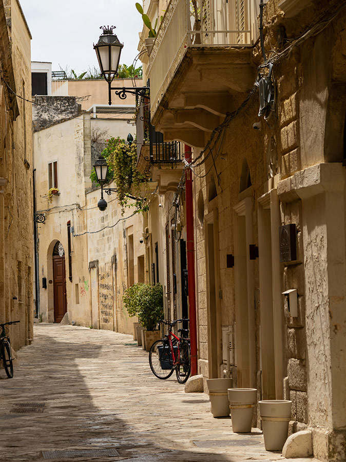 An empty, typical Italian narrow street with beige and brown buildings and a parked bicycle
