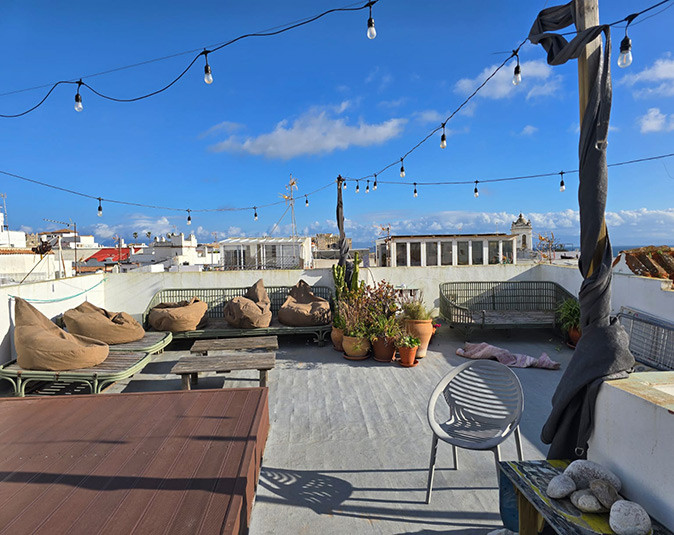 Roof terrace at a coliving in Tarifa A roof terrace with several chairs and bean bags overlooking a Spanish town with white buildings