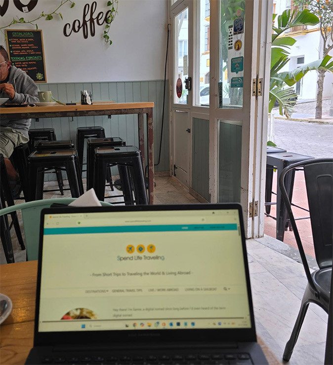 Working remotely from Tarifa, Andalusia, Spain A wooden table with a laptop inside a small cafe showing other tables and chairs