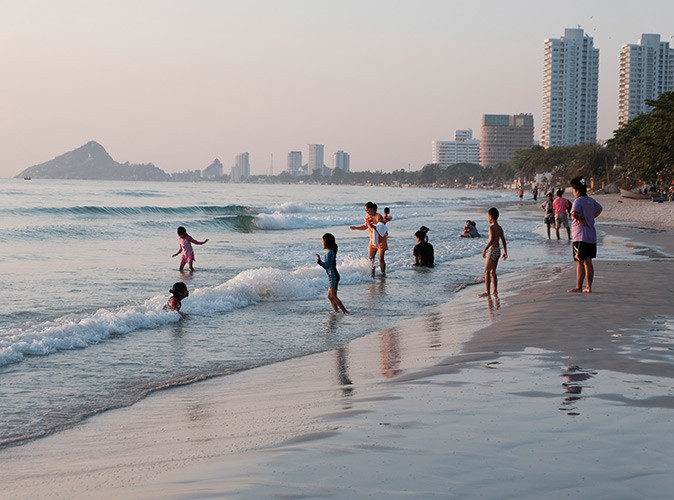 What Hua Hin is really like Kids playing in the water off a sandy beach with sime highrise buildings in the distance